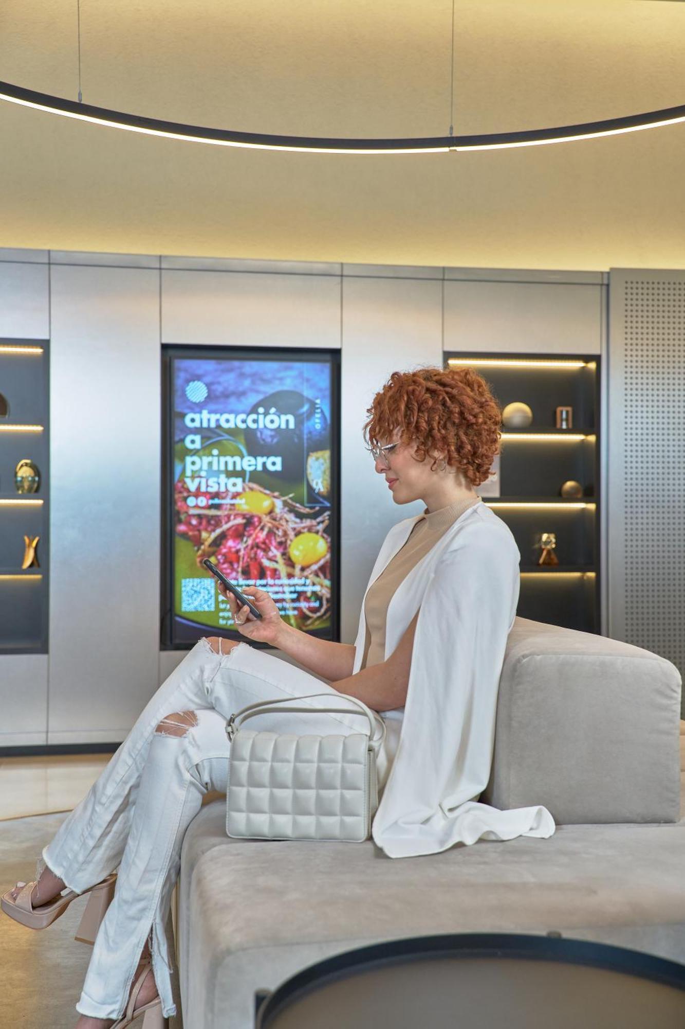 Pullman Santiago Vitacura Extérieur photo A woman using a mobile phone to interact with a digital signage display